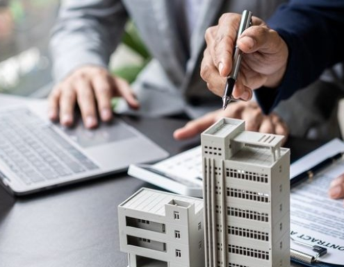 businessman holding model small building_shutterstock_2297877821 1030x385