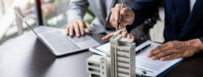 businessman holding model small building_shutterstock_2297877821 1030x385